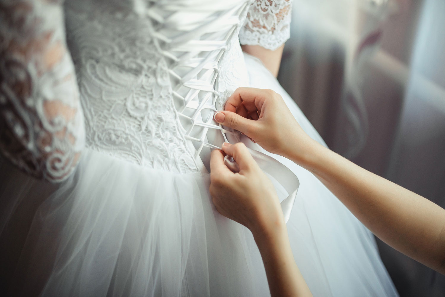 Pessoa ajustando os detalhes finais de um vestido noiva 2023 no corpo de uma mulher
